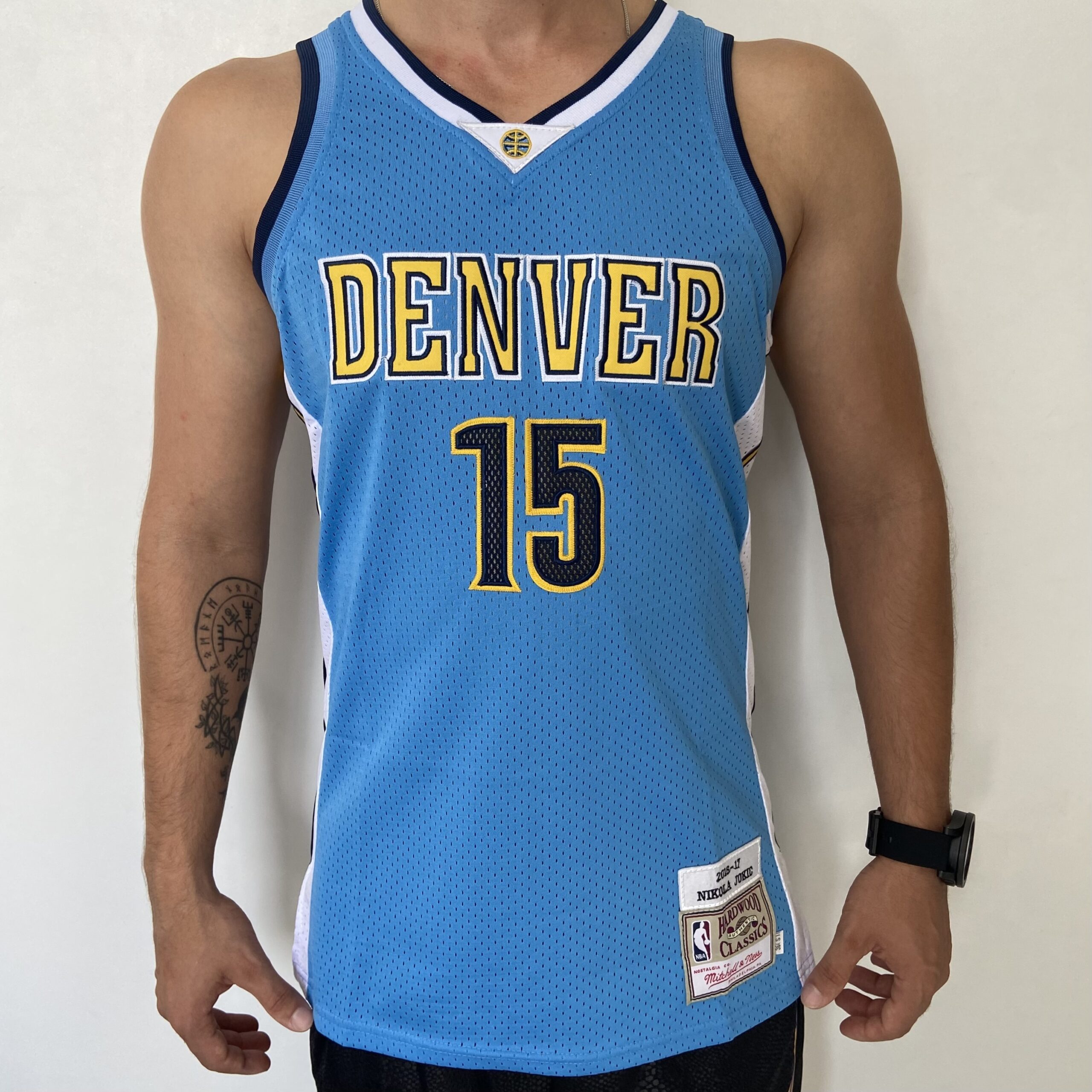2023-09-01 12.16.50 Camiseta Regata NBA Camiseta Regata NBA Mitchell & Ness 2016/17 – Denver Nuggets – Nikola Jokic 15 – Azul Celeste - Imagem 1